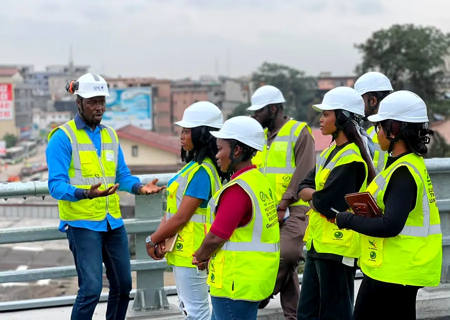 Un ingénieur explique le chantier aux étudiants, tous en gilet et casque de sécurité